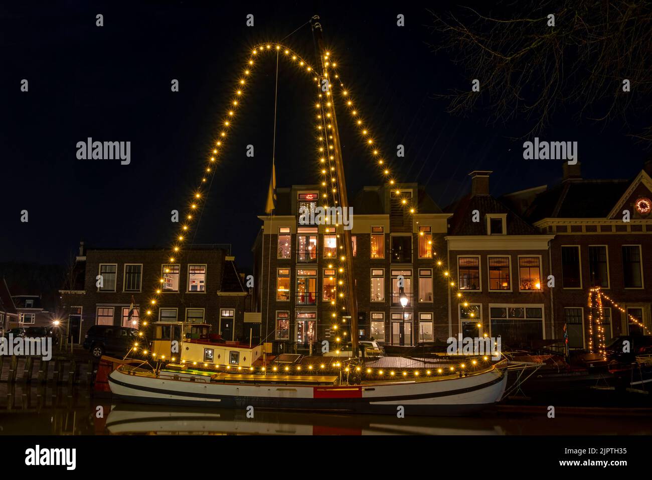 Decorated traditional sailing boats in the harbor from Harlingen in the Netherlands at night Stock Photo