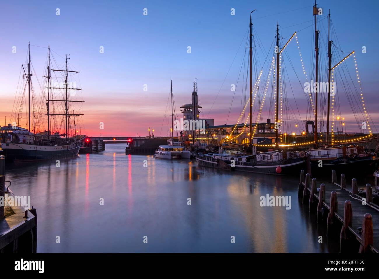 Harbor from Harlingen with decorated sailing boats in Friesland the Netherlands at sunset Stock Photo