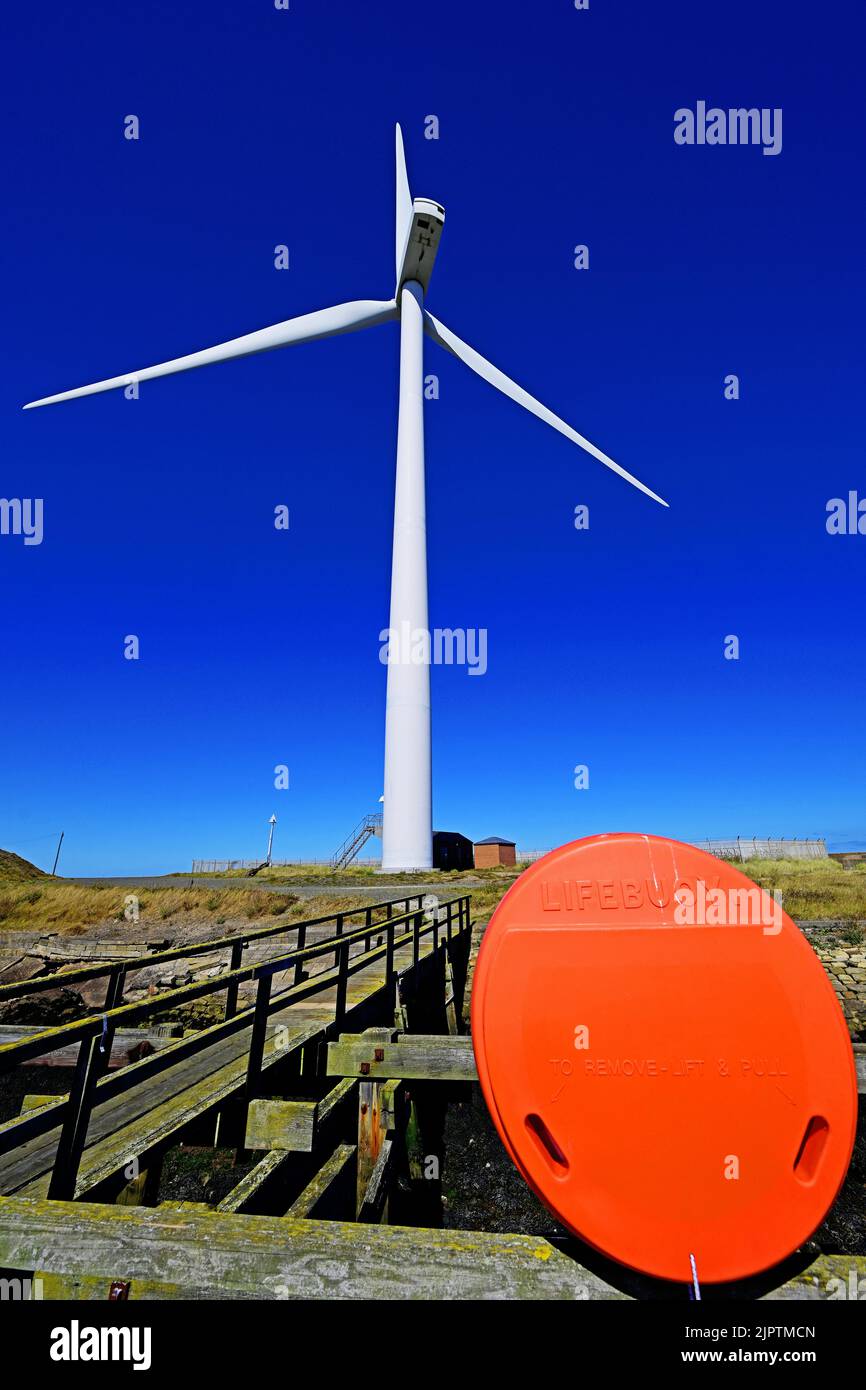 Cambois port Blyth Northumberland single wind turbine by the wooden jetty with a safety lifebelt against deep blue sky Stock Photo