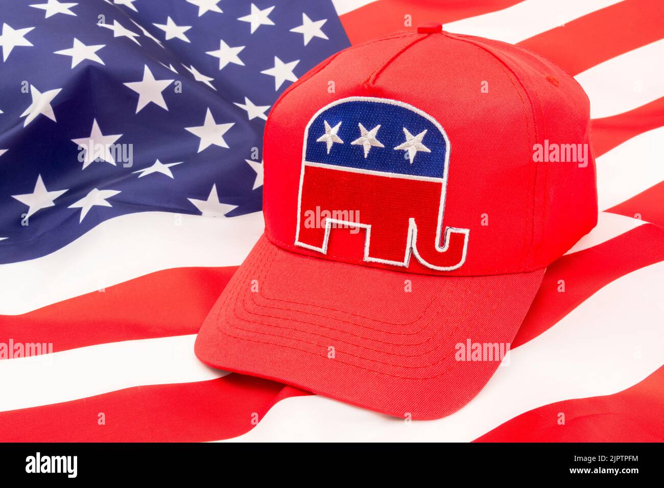 Red MAGA-type cap & Republican Elephant logo & US Stars and Stripes backdrop flag. For 2024 US Presidential election in November & Republican Red Wave Stock Photo