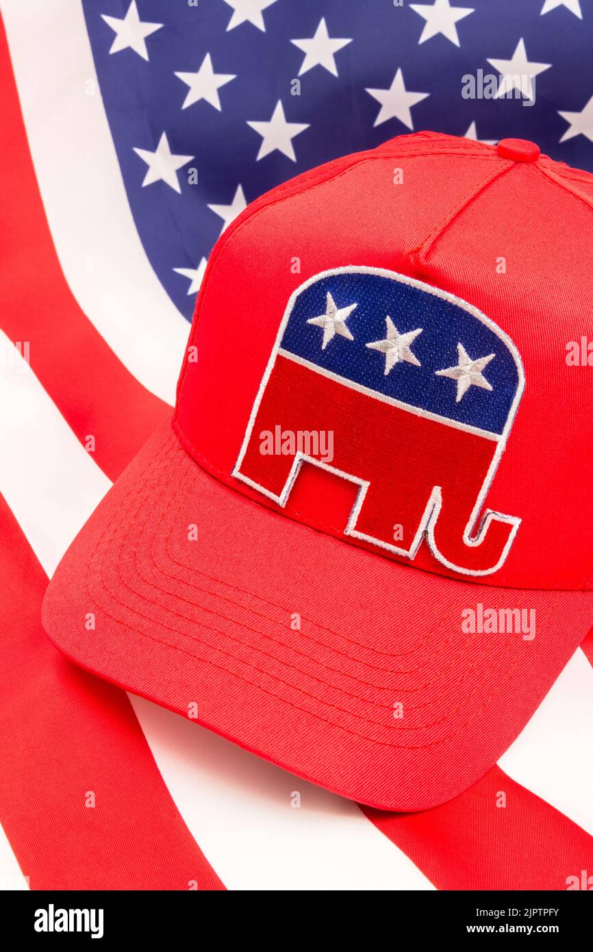 Red MAGA-type cap with Republican Elephant logo & US Stars and Stripes backdrop flag. For November 2024 US Presidential election & Republican Red Wave Stock Photo
