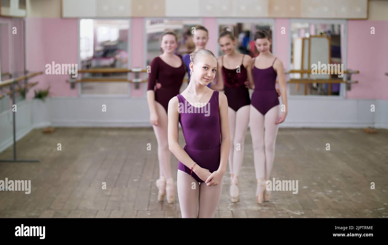 portrait of a young girl ballet dancer in a lilac ballet leotard, smiling, gracefully performing a ballet figure. High quality photo Stock Photo