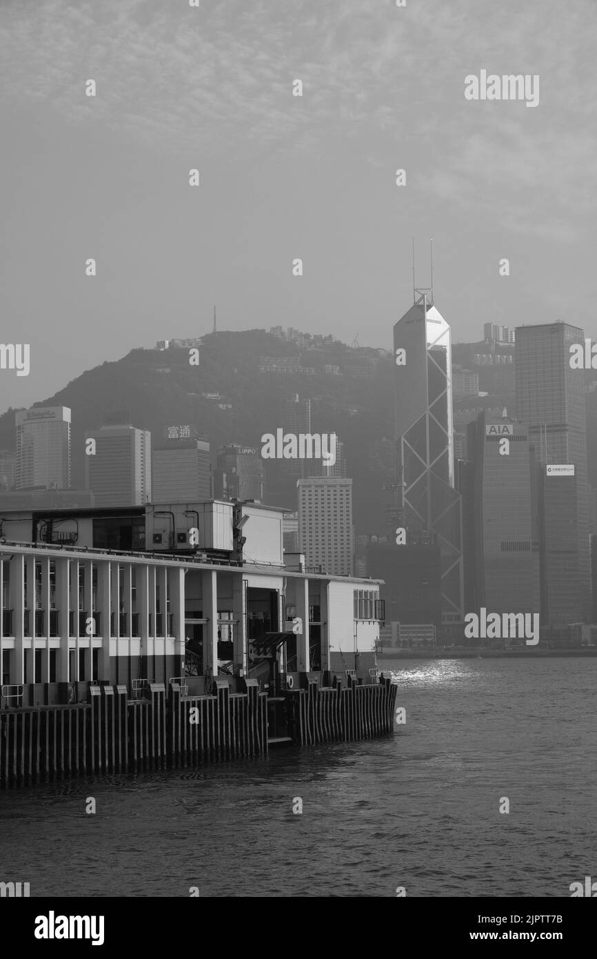 Star Ferry Pier at Tsim Sha Tsui Hong Kong Black White Photo Coloured Star Ferry Green White Ferry Background is Central of Hong Kong Island IFC Stock Photo