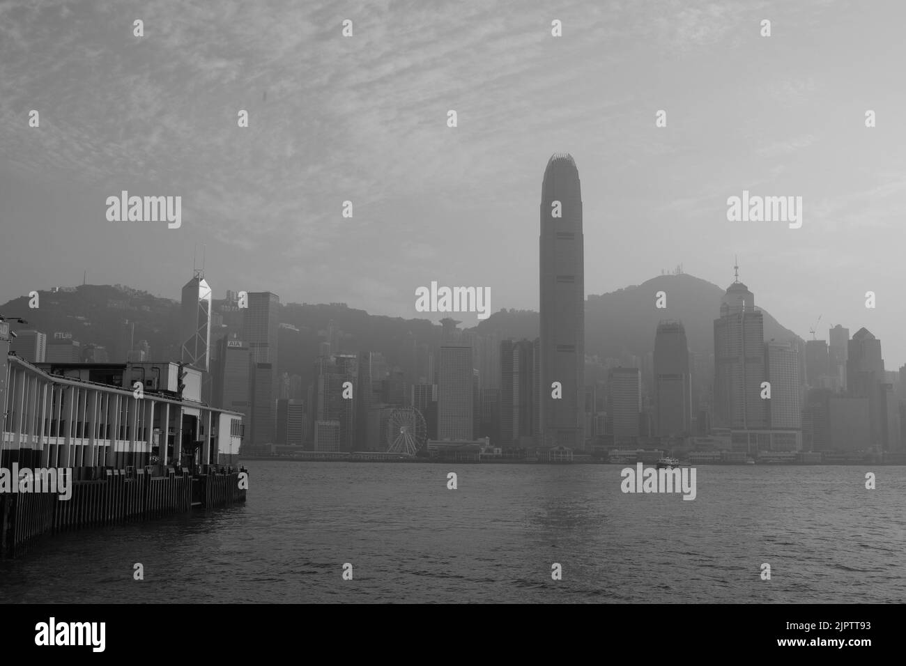 Star Ferry Pier at Tsim Sha Tsui Hong Kong Black White Photo Coloured Star Ferry Green White Ferry Background is Central of Hong Kong Island IFC Stock Photo