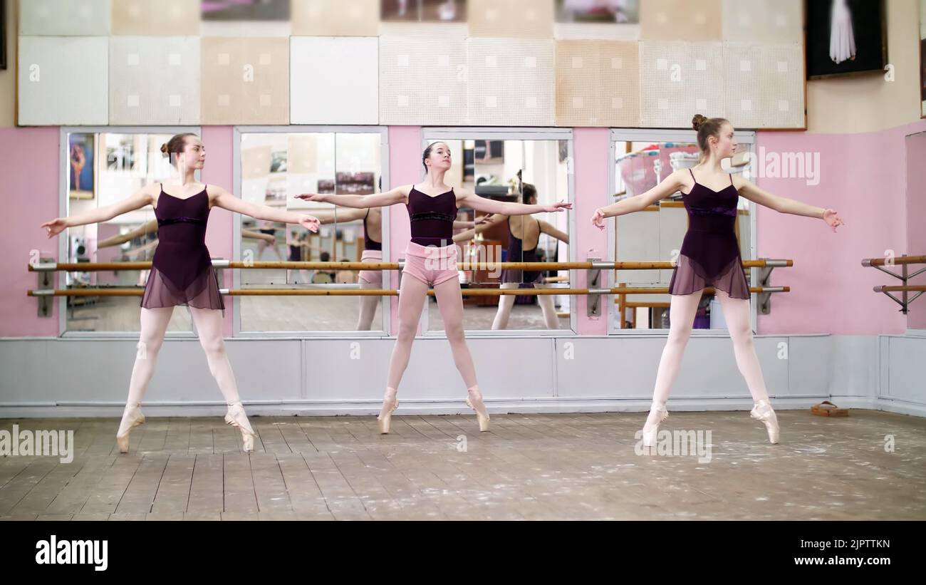 in dancing hall, Young ballerinas in black leotards perform pas echappe