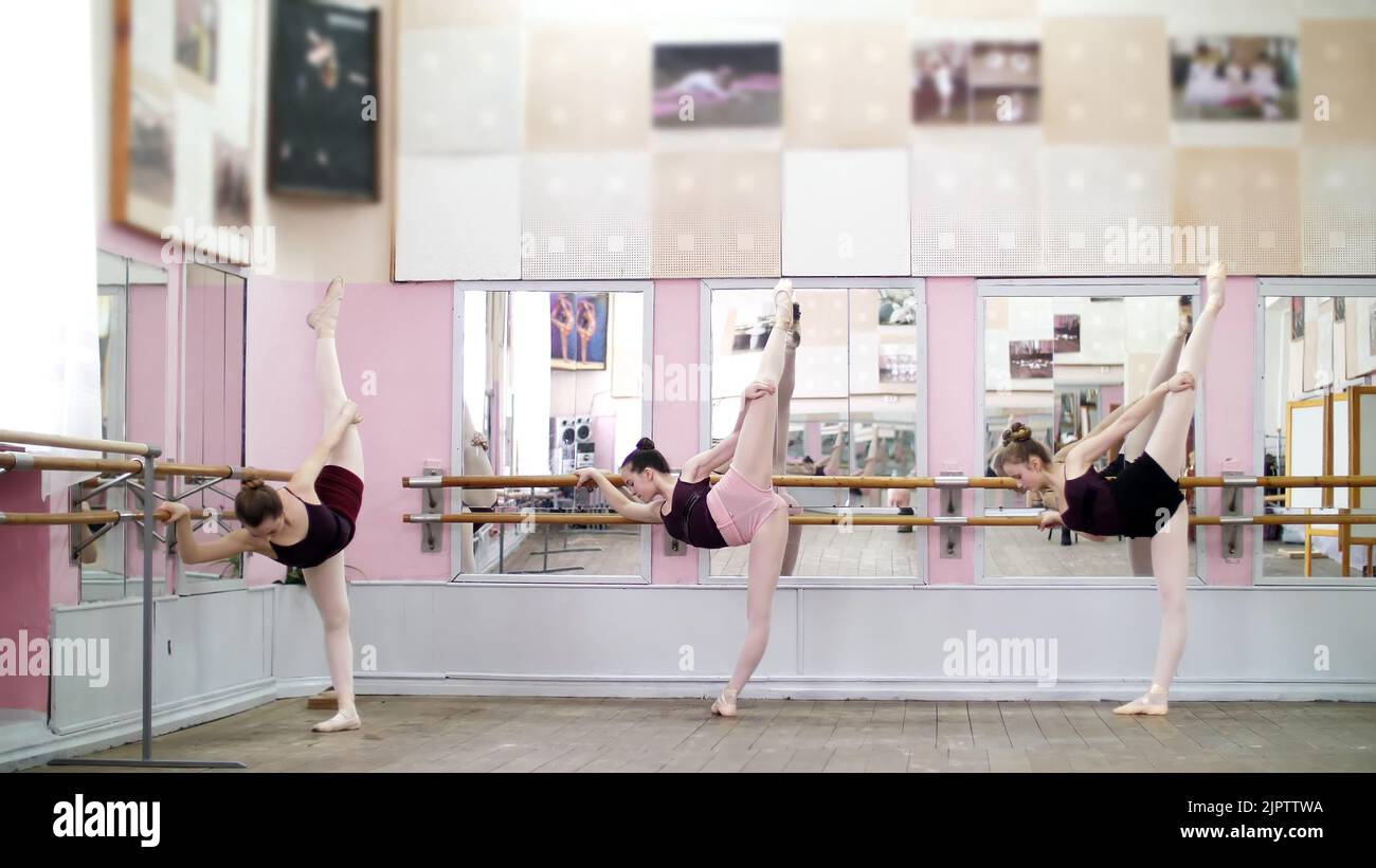 in dancing hall, Young ballerinas in black leotards are stretching
