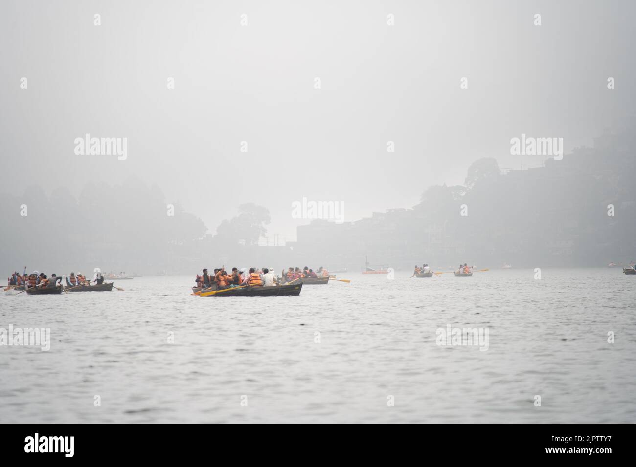 foggy lake at bhimtal filled with row boats piloted by locals carrying tourists come to visit this famous hill station in the monsoons for the natural Stock Photo