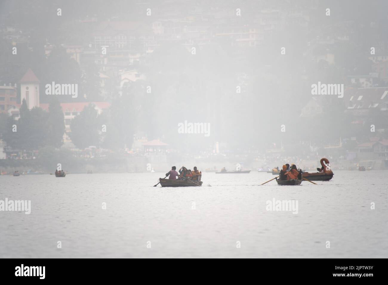 foggy lake at bhimtal filled with row boats piloted by locals carrying tourists come to visit this famous hill station in the monsoons for the natural Stock Photo