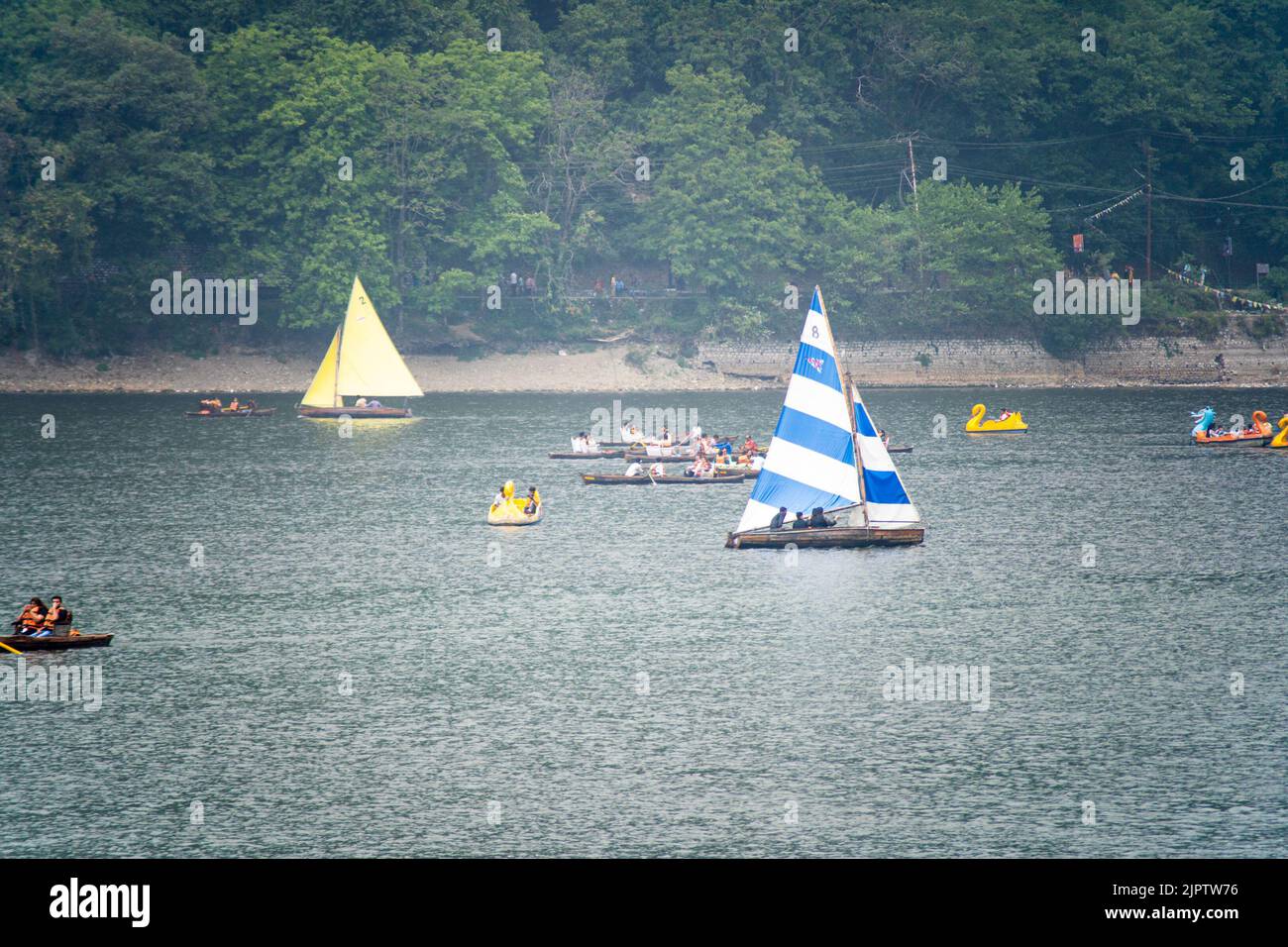 four colorful sailboats lost in the haze fog with smaller pedal row boats floating around on the