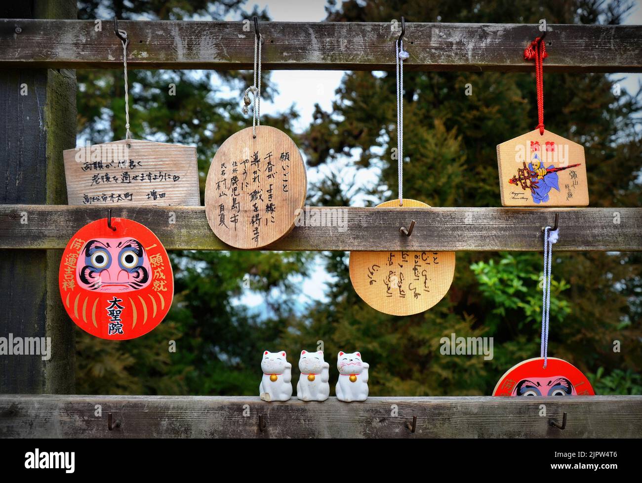 Japanese prayer plaques called Ema, and cat figurines called maneki-neko in Japanese (literally “beckoning cat”). Mount Misen, Miyajima island, Japan. Stock Photo