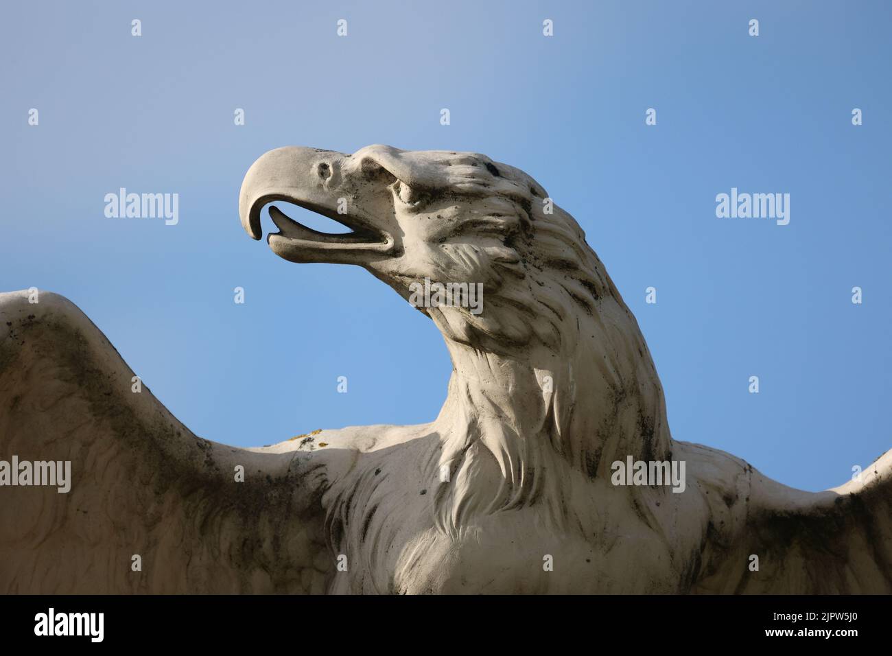 A closeup shot of a beautiful stone sculpture of an eagle under the blue sky Stock Photo