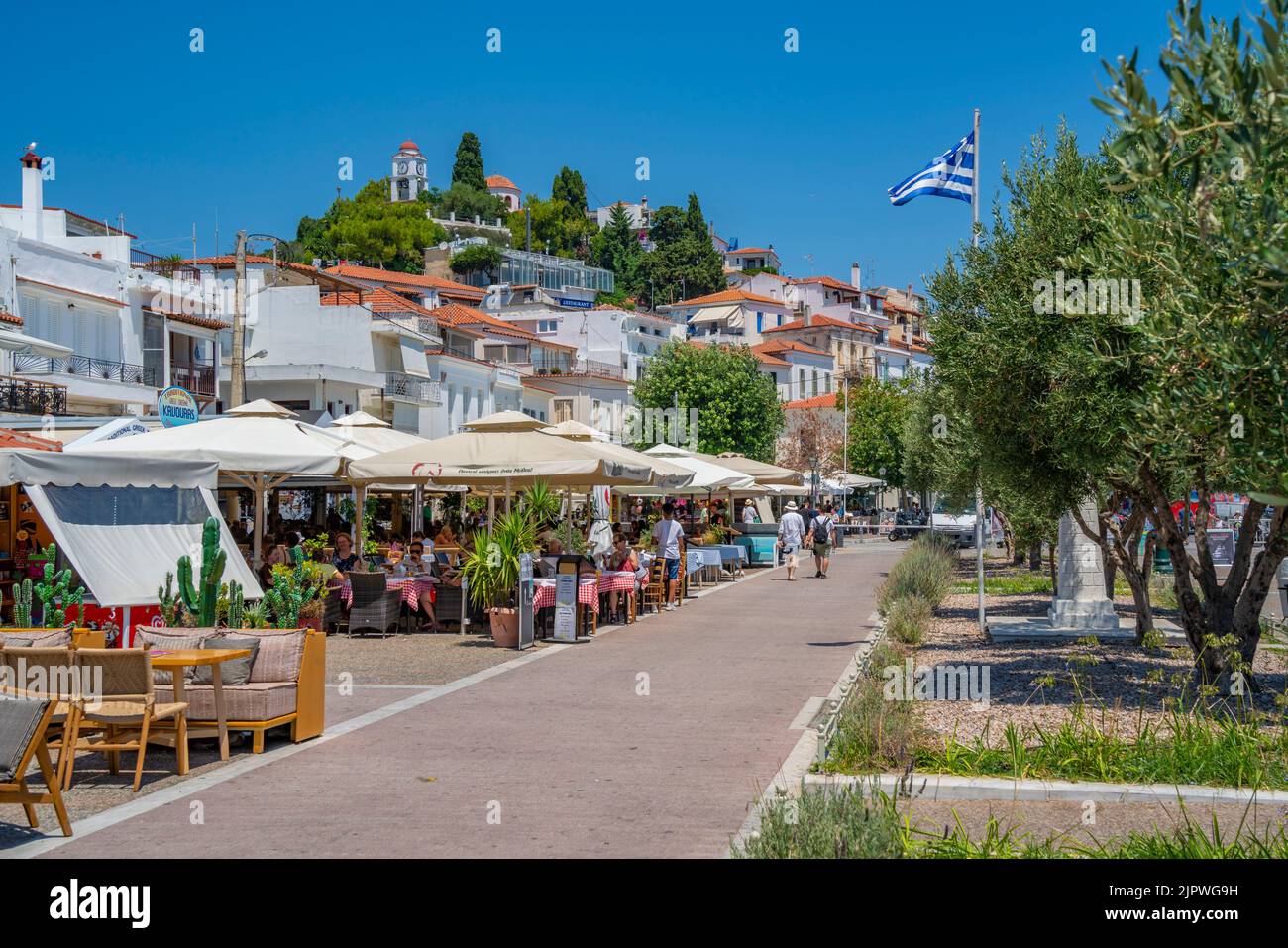 View of sea front restaurants overlooked by Greek Orthodox Church, Skiathos Island, Sporades Islands, Greek Islands, Greece, Europe Stock Photo