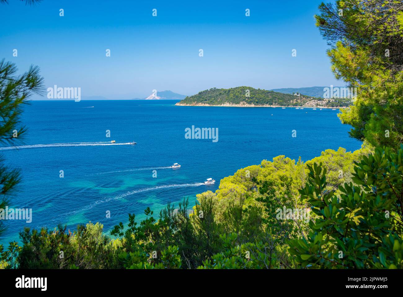 View of boats in the Aegean Sea and alpine coastline near Maratha Beach, Skiathos Island, Sporades Islands, Greek Islands, Greece, Europe Stock Photo