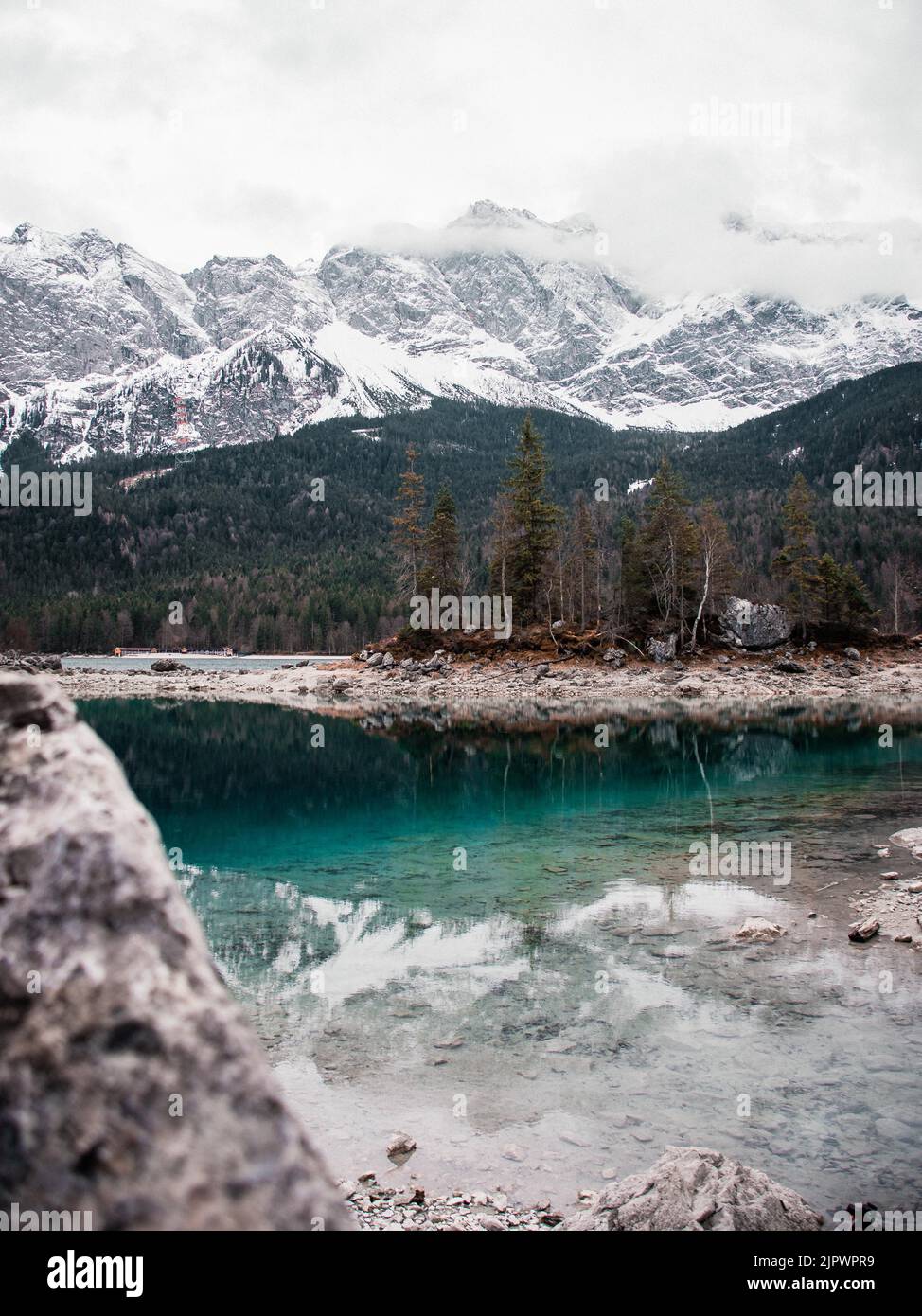 A Vertical Shot Of The Scenic Eibsee Lake Coast Against Forest And a-vertical-shot-of-the-scenic-eibsee-lake-coast-against-forest-and