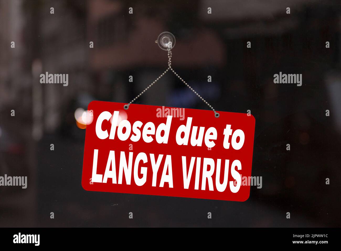 Close-up on a red sign in the window of a shop displaying the message in English - Closed due to Langya virus -. Stock Photo