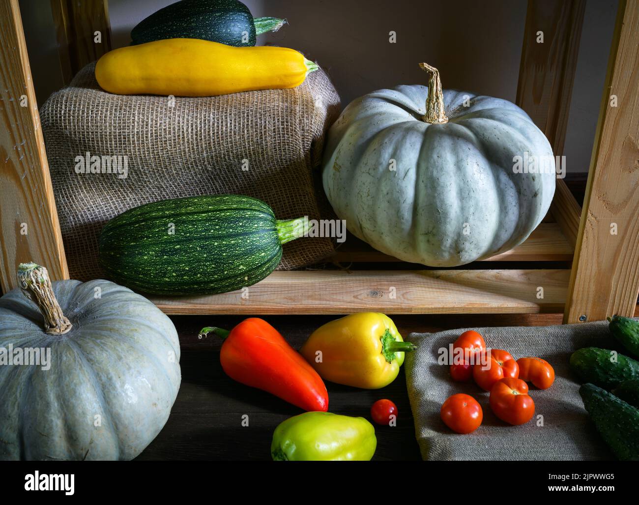 Pumpkins, vegetable marrow and sweet pepper in kitchen, vintage still life of organic food. Photo of zucchini and tomatoes in rustic interior. Concept Stock Photo