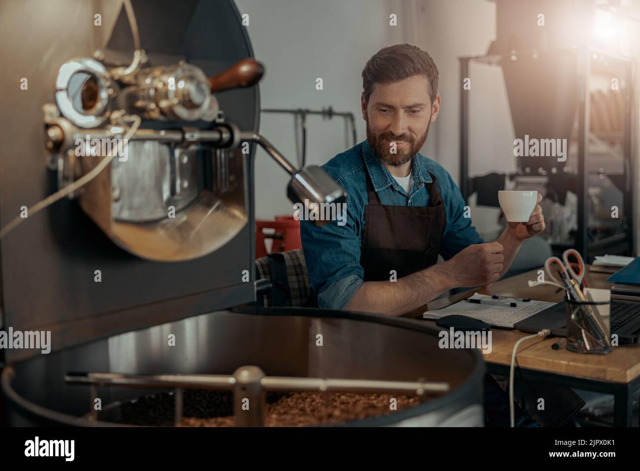 Business owner of coffee roasting factory working and drinking coffee