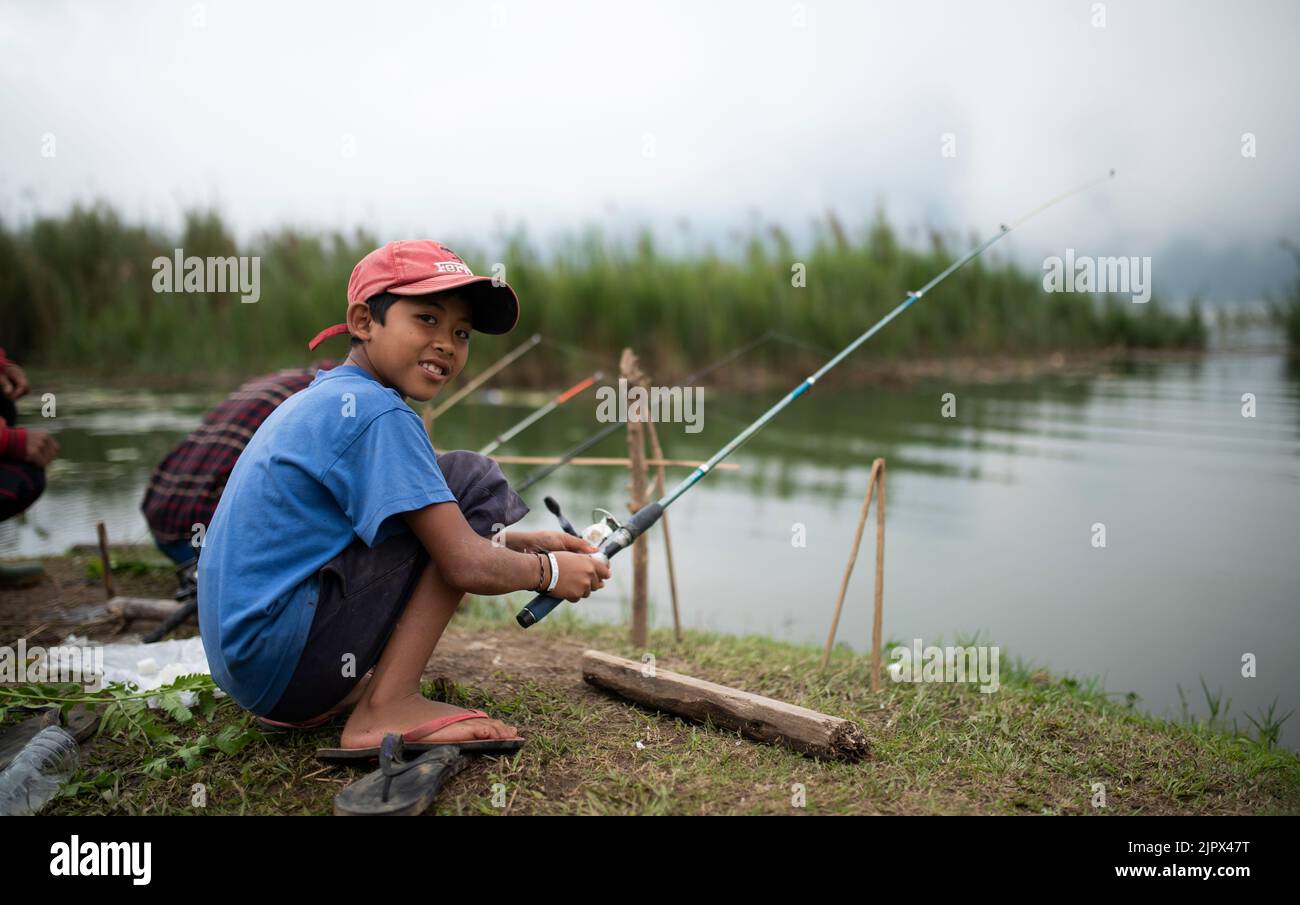 UBUD, BALI, INDONESIA, MAY 15, 2017; Portrait of boy and his father fishing by Beratan lake. Indonesian boy image. Stock Photo