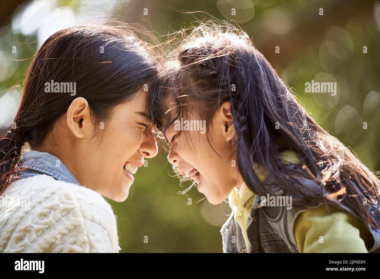 asian mother and daughter having a good time outdoors in city park Stock Photo