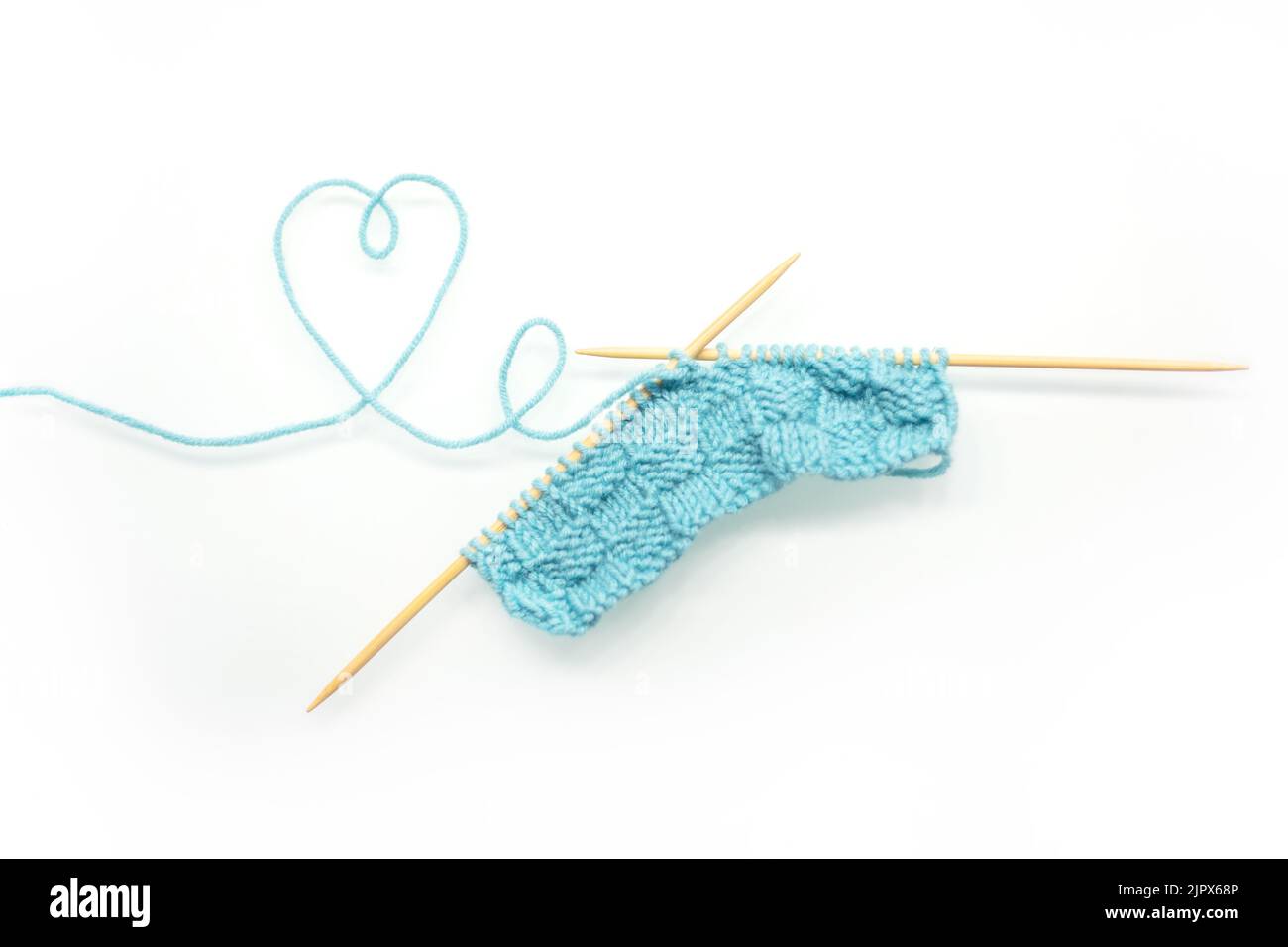 Knitting needles from wool and cotton. knitted product on knitting needles on a white background. Stock Photo