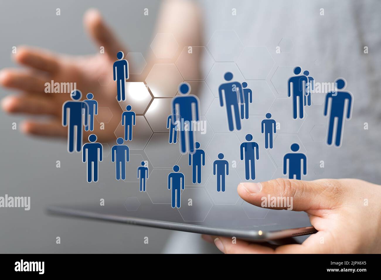 A 3D rendering of people icons floating above a tablet in a person's ...
