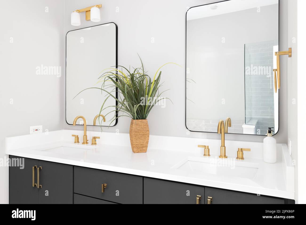 Bathroom a grey vanity, gold lights and faucets, and white marble countertop. Stock Photo