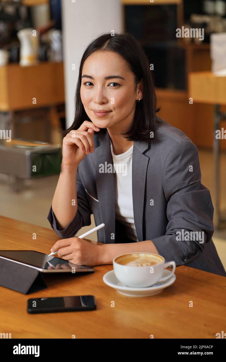 Young happy Asian business woman using digital tablet, vertical portrait. Stock Photo