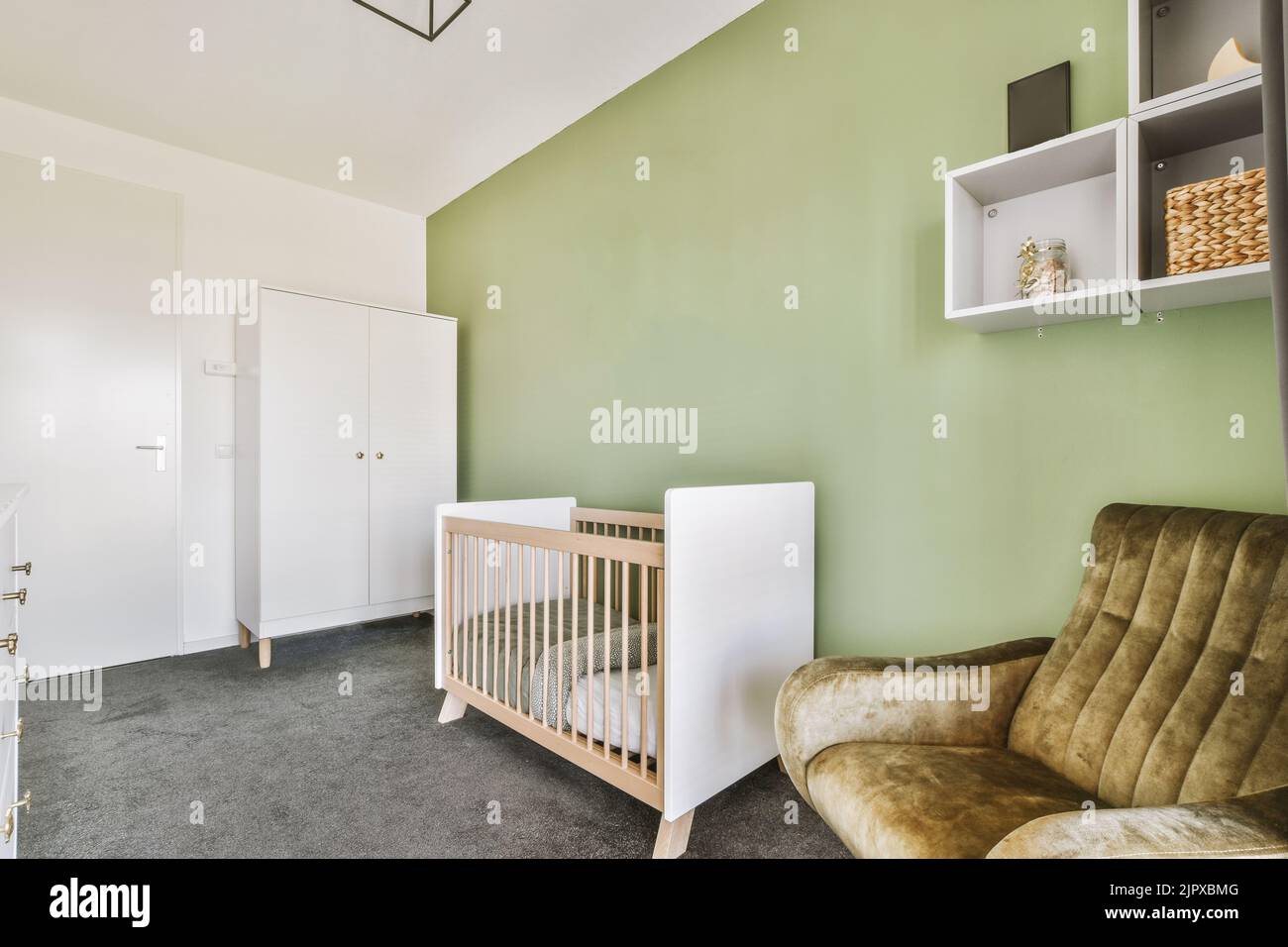 Interior of white room with baby crib and armchair near window in