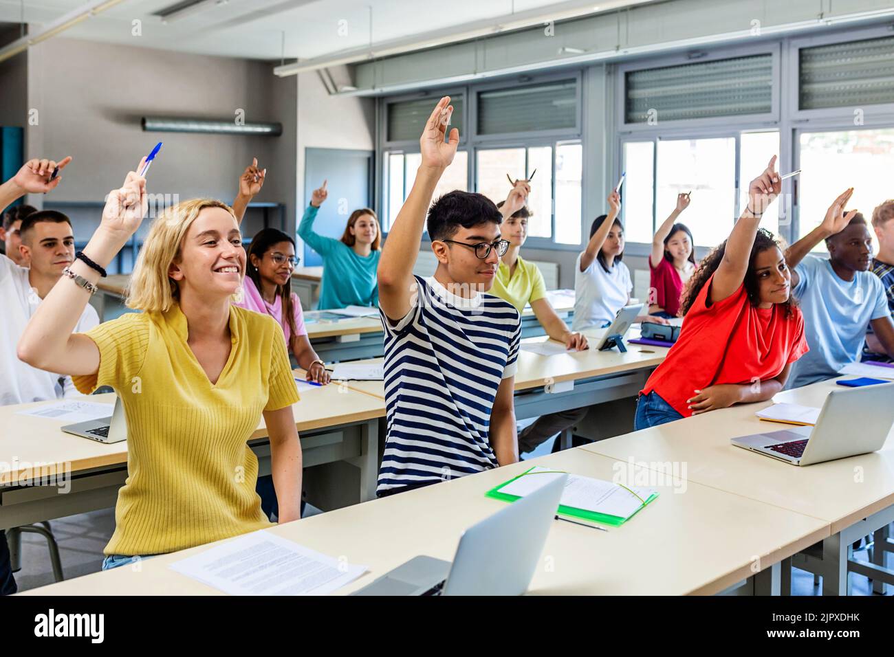 High school students raising hand to ask a question during lecture in