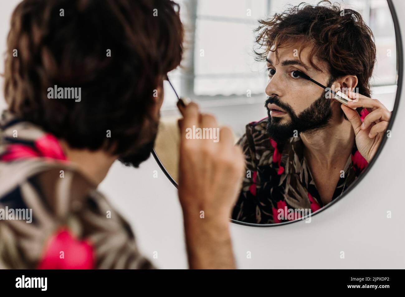 Young homosexual man applying eyelashes sitting at a dressing table Stock Photo