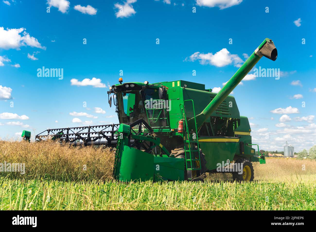 A big modern green combine harvester with a cutting bar or revolving ...