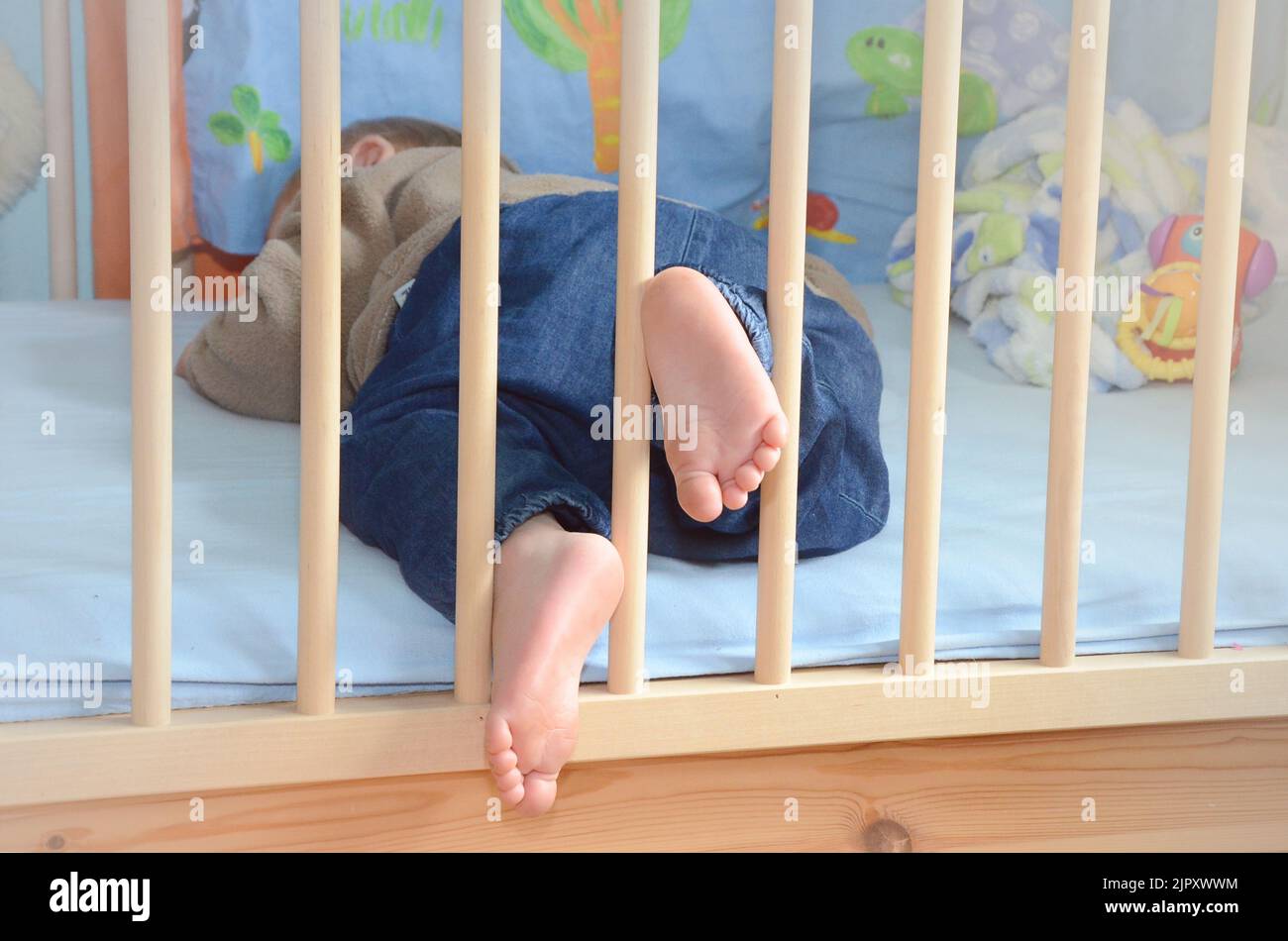 A child sleeping in a cot and sticking the feet out Stock Photo Alamy