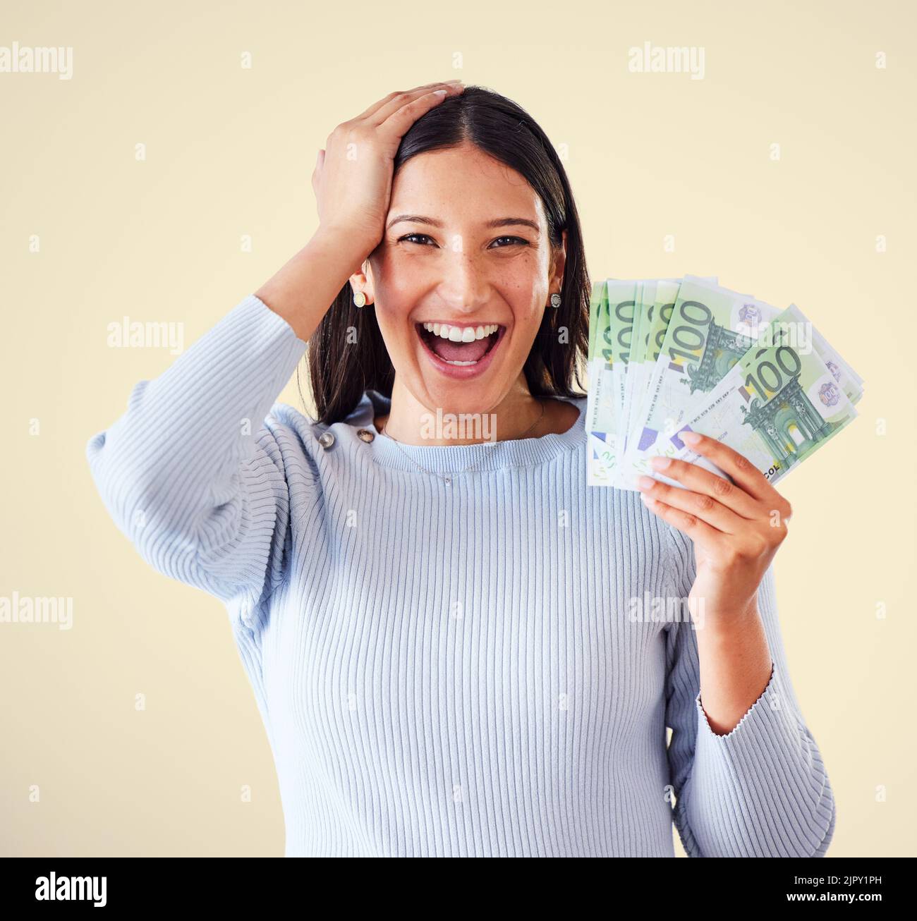 Woman celebrating success, winning money or lottery victory, holding cash or banknotes in hand. Portrait of excited, happy and proud winner screaming Stock Photo