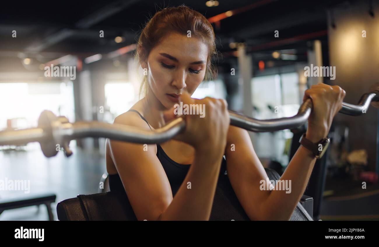 Sporty woman exercising with barbell in fitness class. Workout woman in gym with barbell. Stock Photo