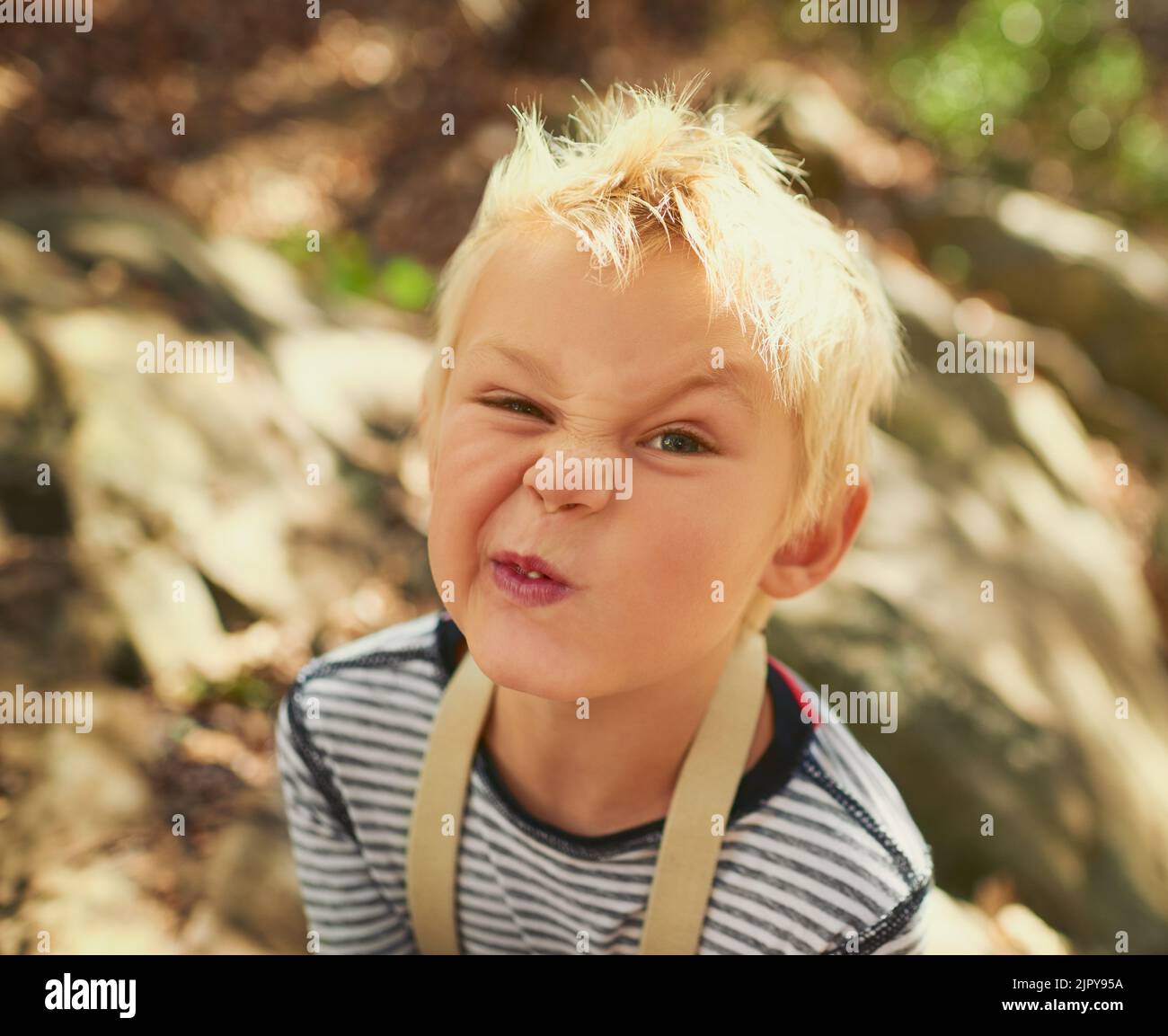 Whats the funniest face you can pull. Portrait of an adorable little boy playing outdoors. Stock Photo