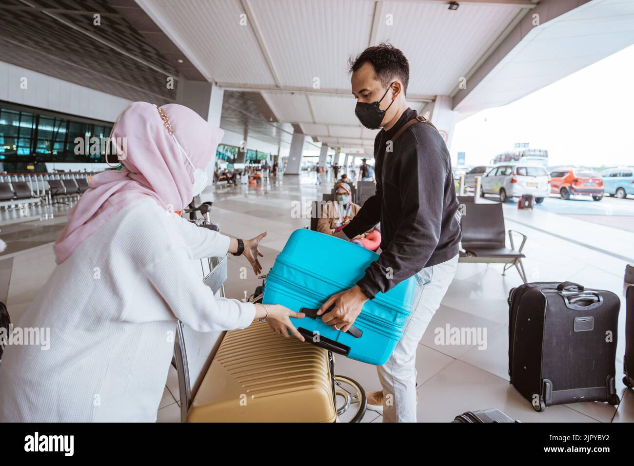 muslim woman and husband carrying a luggage in the airport Stock Photo ...