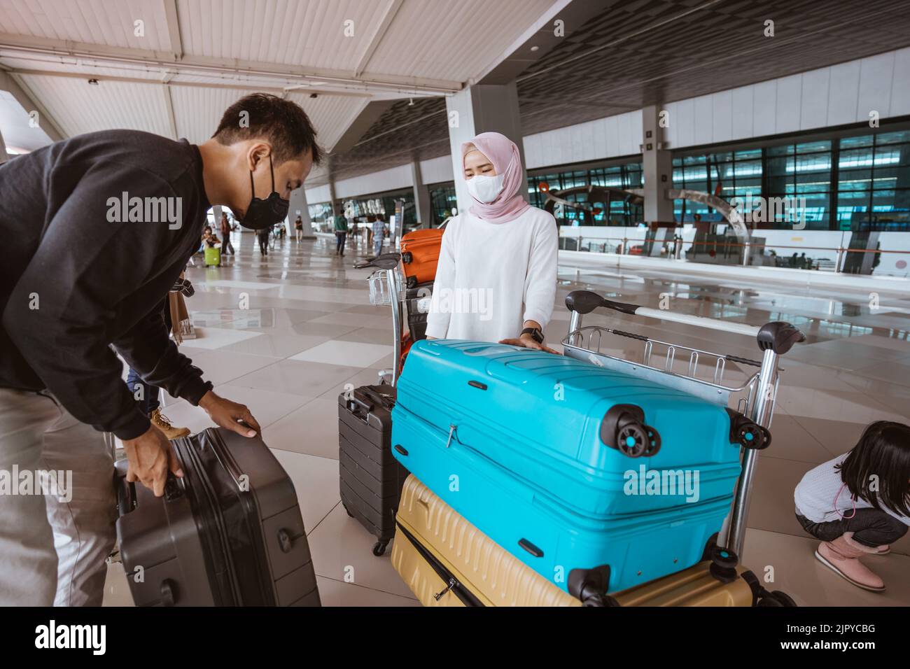 muslim woman and husband carrying a lugage in the airport Stock Photo ...