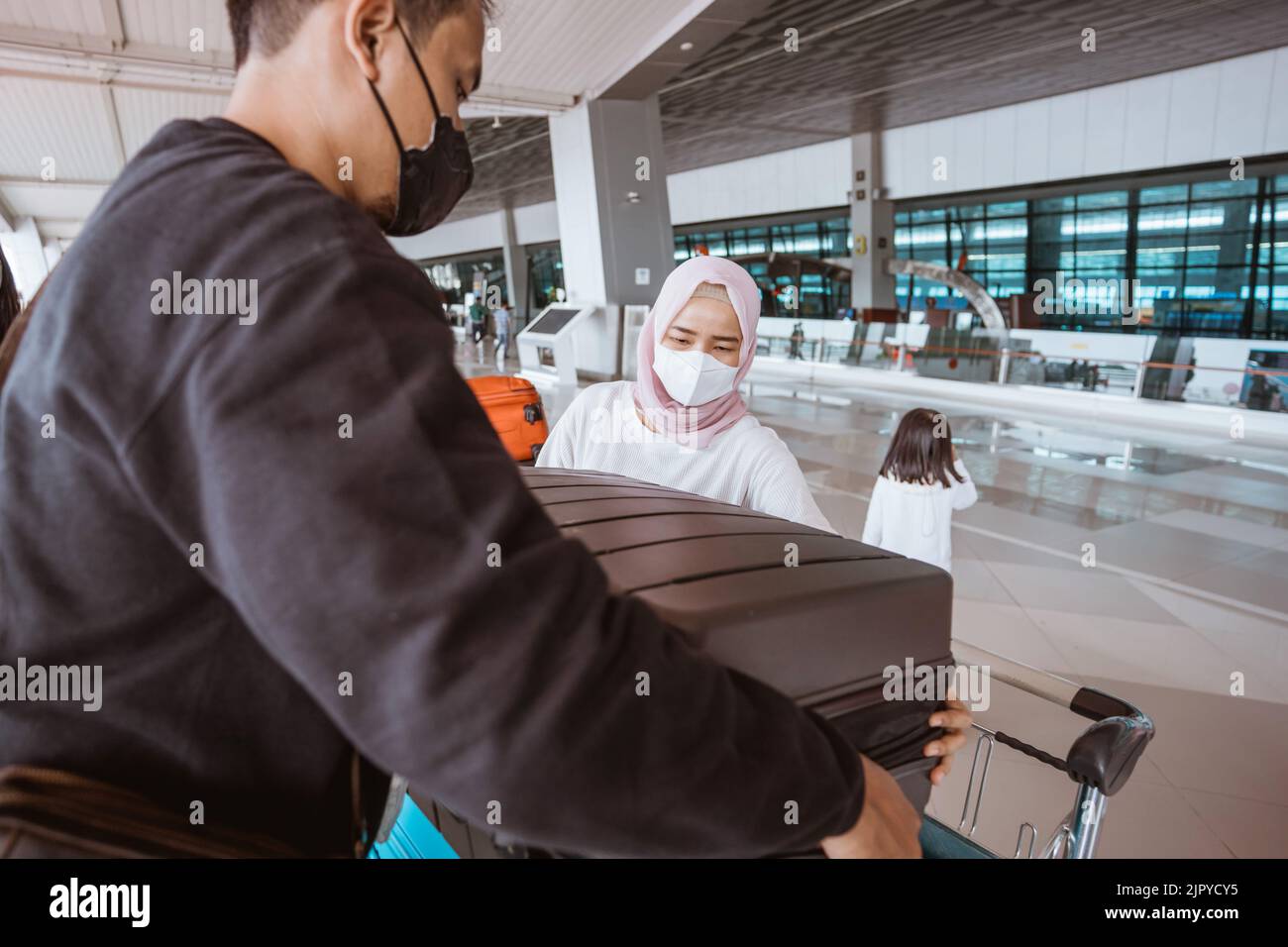 muslim woman and husband carrying a lugage in the airport Stock Photo ...