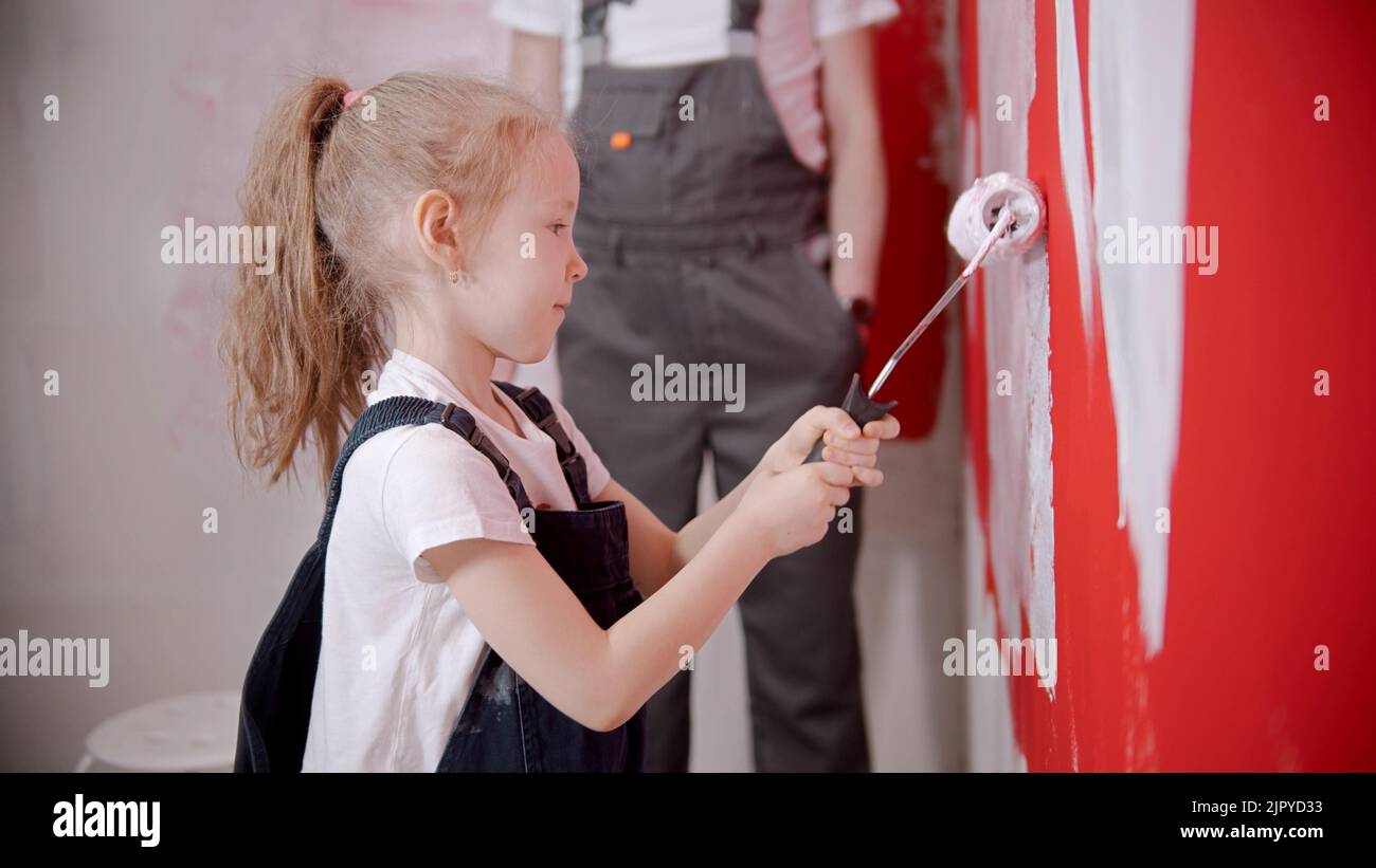 A little girl painting wall with a paint roller Stock Photo