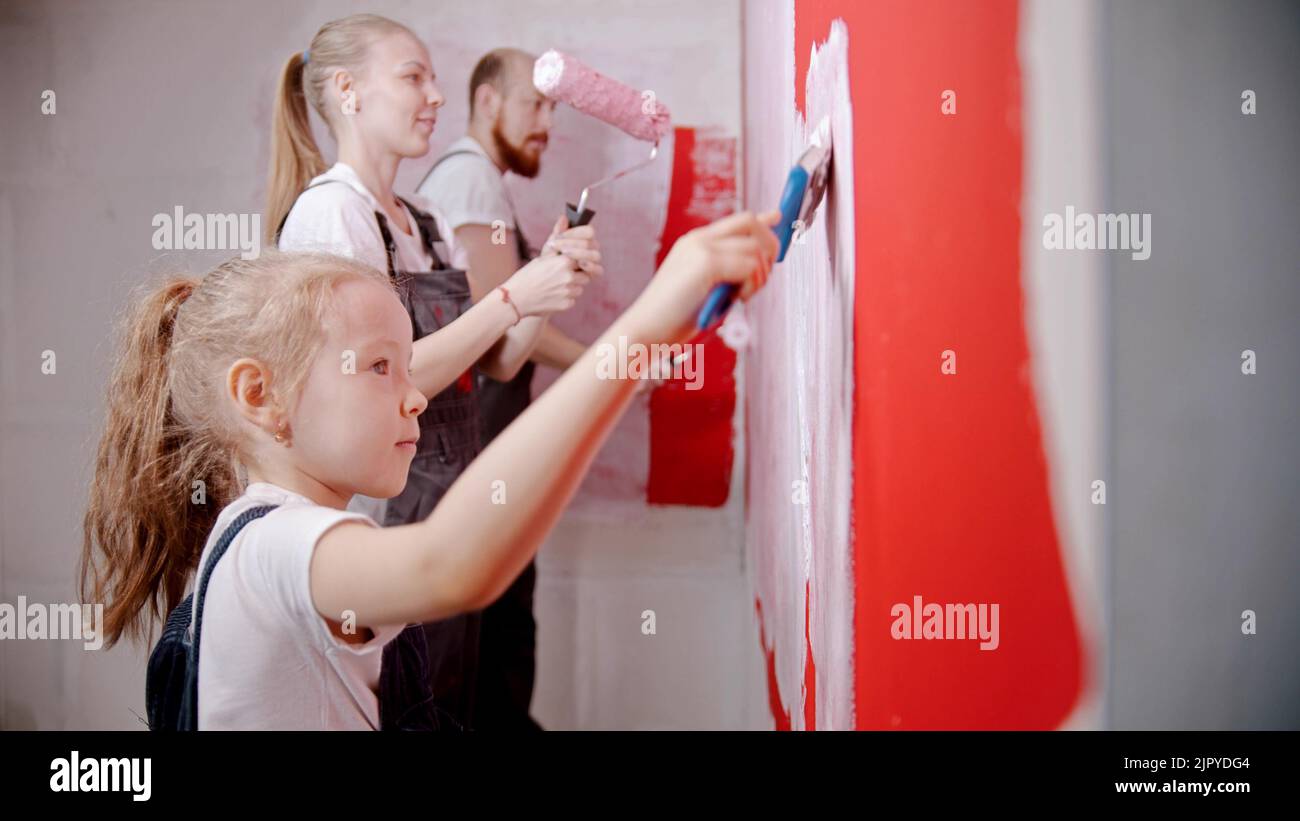 Family painting walls in red in the new apartment a little girl