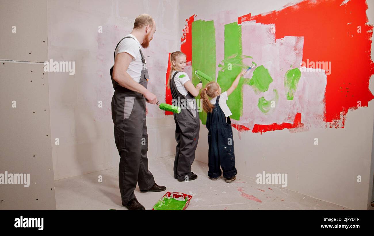 Funny family painting walls in the new apartment in green and red colors Stock Photo