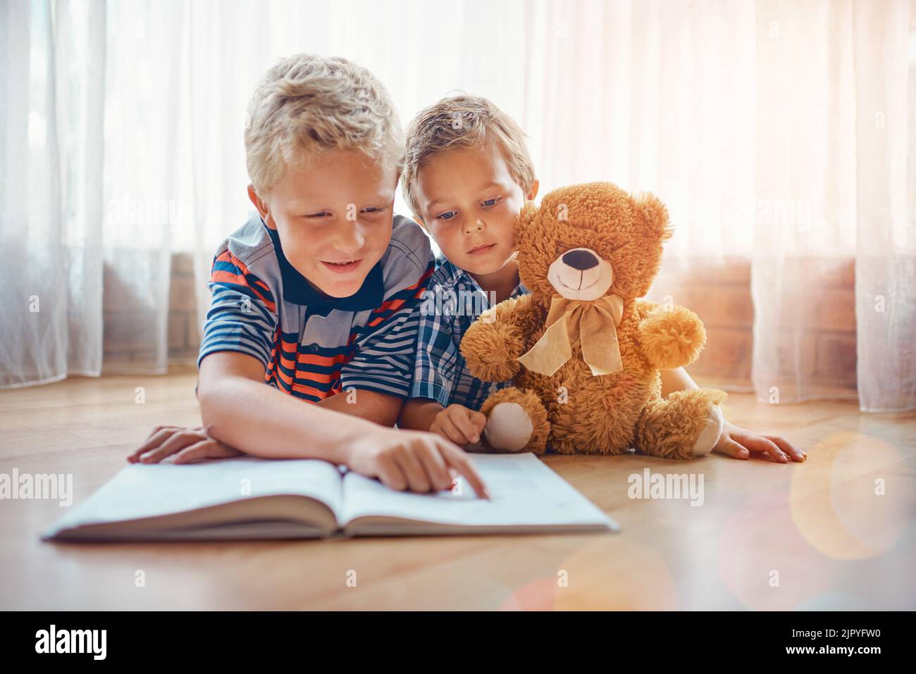 Hes such a good big brother. a boy reading to his younger brother. Stock Photo