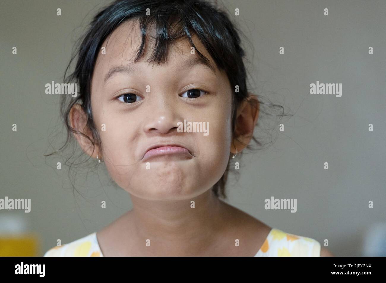 Happy cute asian girl Child looks at the camera and makes a funny ...