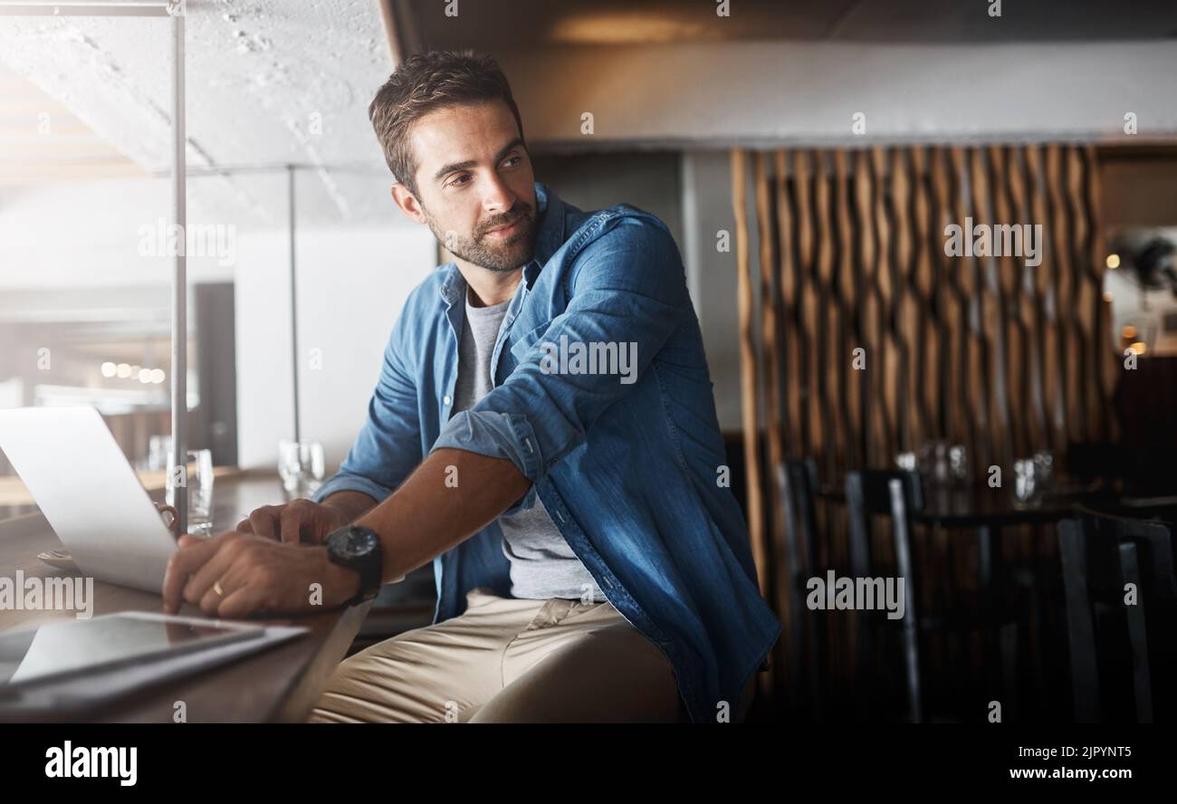 Things can only get better. a handsome young man using a laptop in a coffee shop. Stock Photo