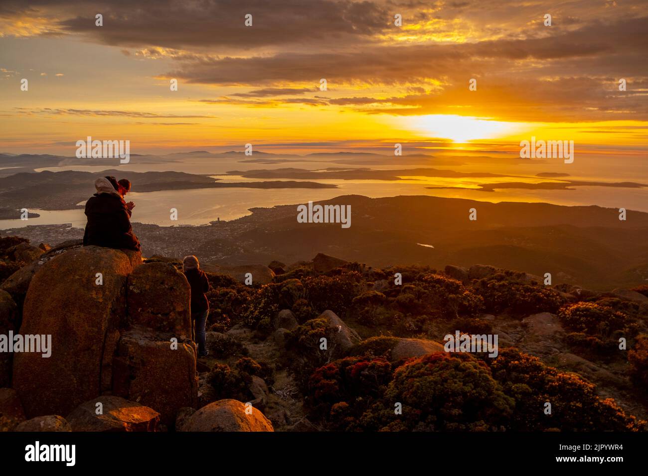 Watching the sun rise over the Derwent River from the summit of kunanyi/Mt Wellington in Hobart Tasmania (altitude 1271 metres above sea level) Stock Photo