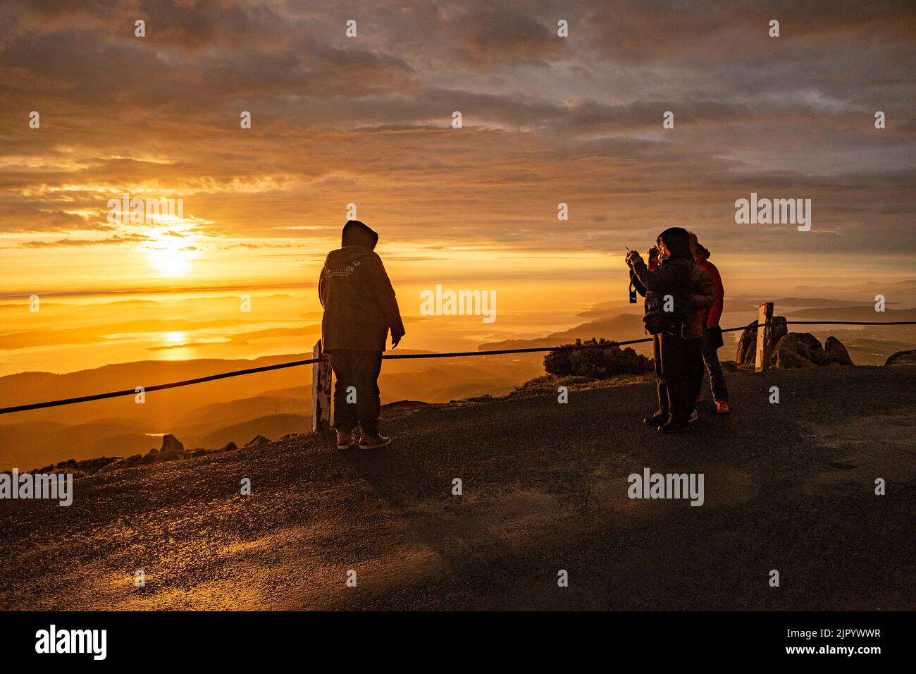 Tourists watching the sunrise from the summit of kunanyi/Mt Wellington in Hobart Tasmania (altitude 1271 metres above sea level) Stock Photo