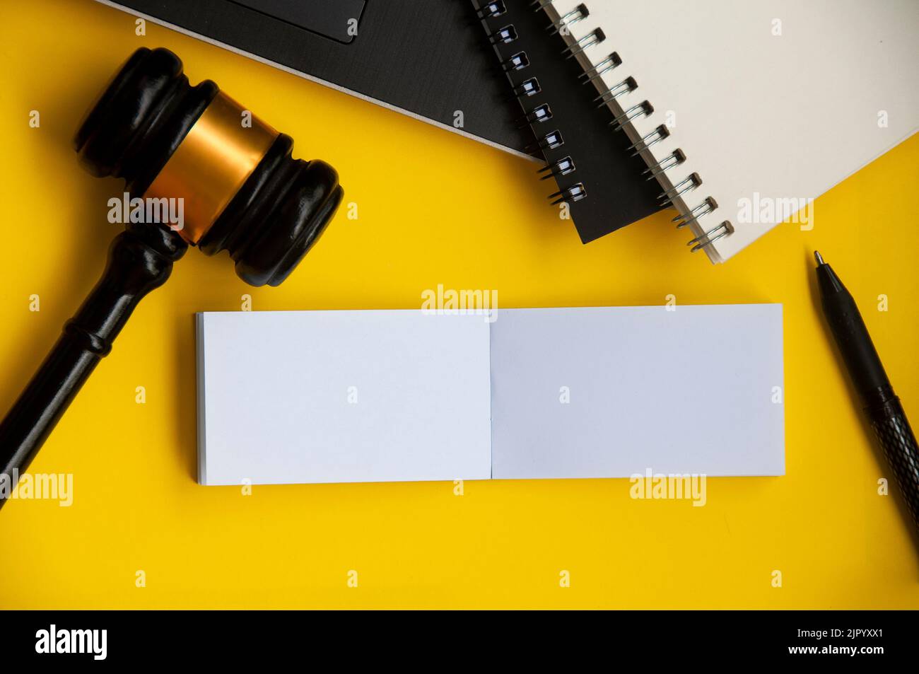 Top view of blank paper note with gavel, laptop and note book on yellow background. Copy space. Stock Photo