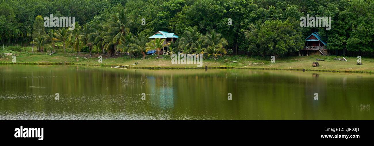 A dreamy landscape, a small house in tropical lush green woods, by a tranquil lake. Stock Photo