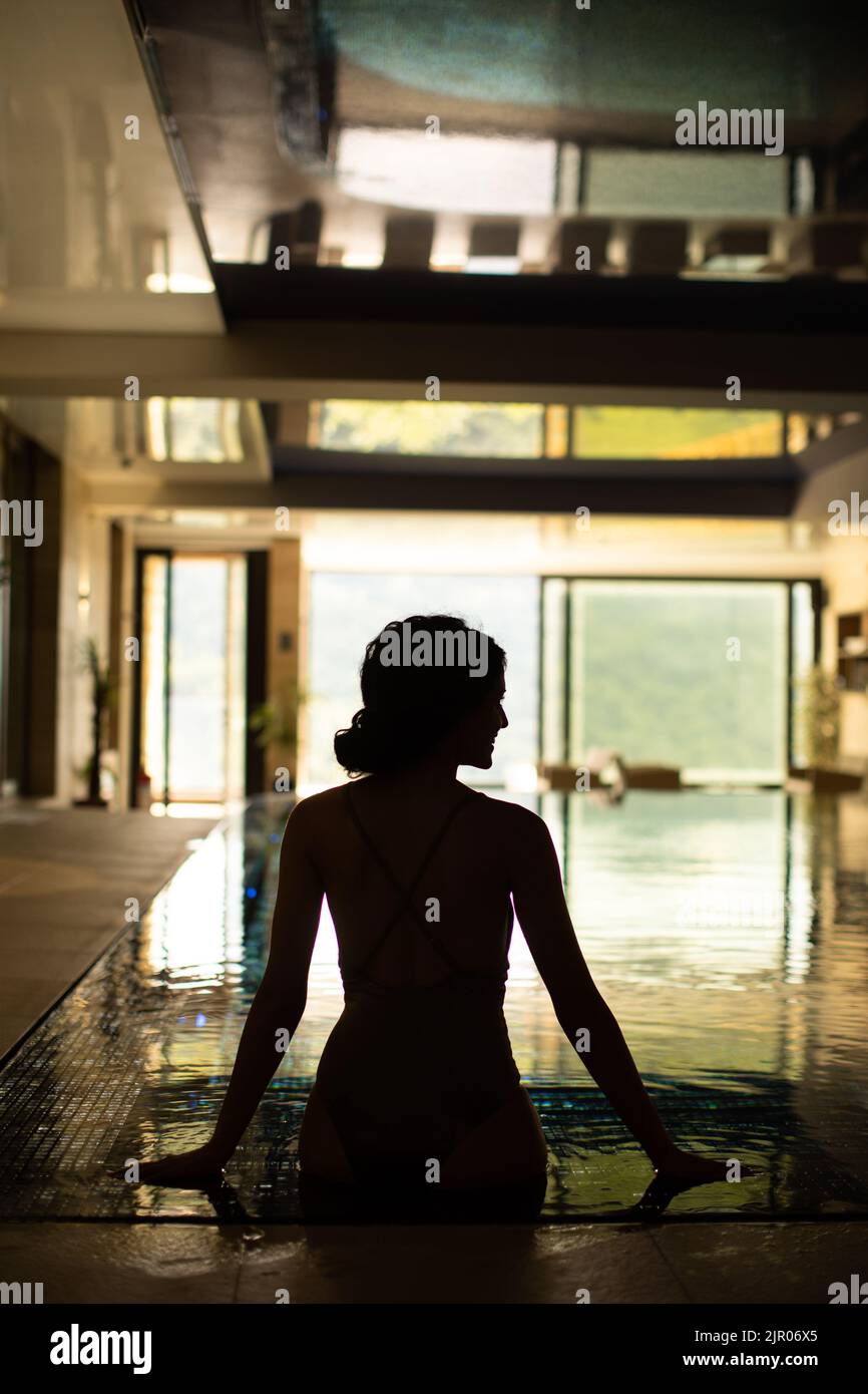 Rear view of pretty young woman relaxing on the poolside Stock Photo ...