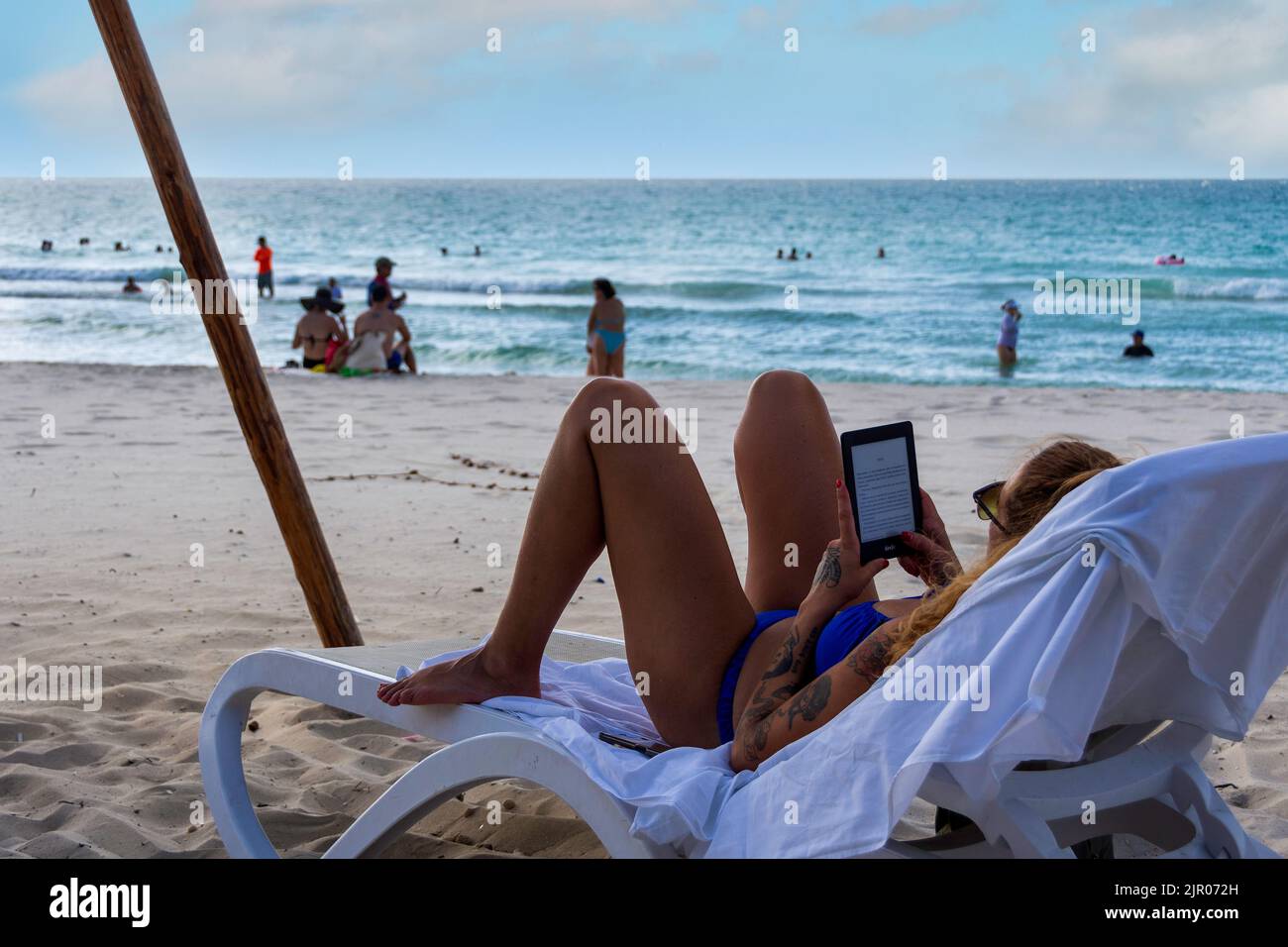 A woman reading a book on her Kindle, Varadero Beach, Cuba. Stock Photo